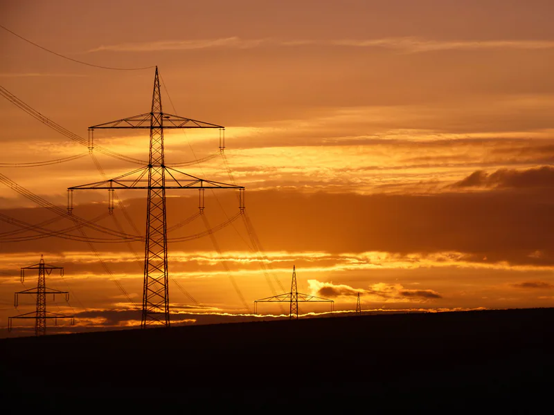 Silhouettes of power lines against a dramatic orange sunset sky in Bornheim, Germany