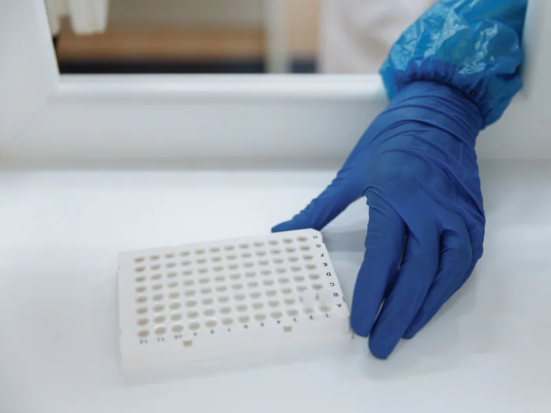 Scientist with protective gloves handling test samples in a sterile laboratory environment