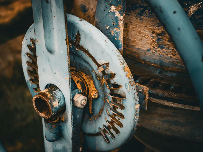 Detail view of a rusty, blue painted industrial machinery component, highlighting texture and decay