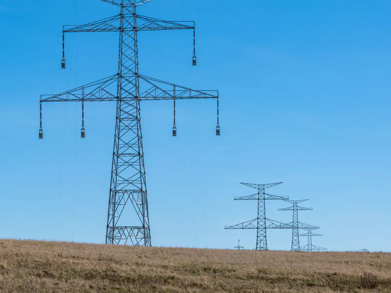 High-voltage transmission towers crossing open countryside