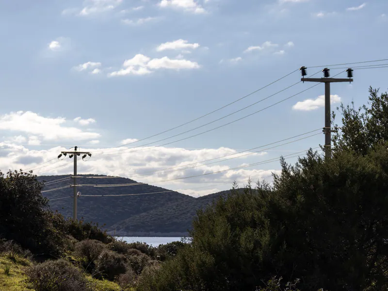 Overhead power line crossing a coastal landscape