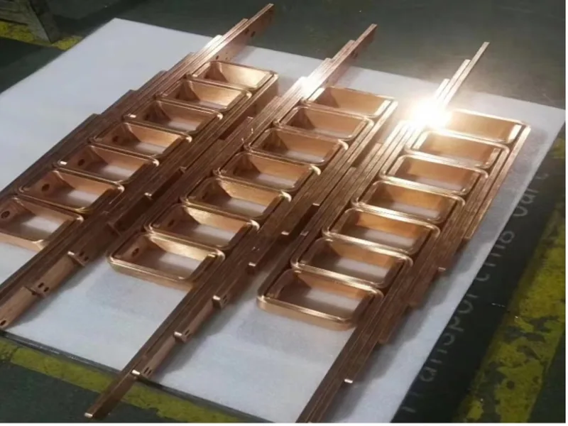 Formed copper busbar samples arranged on a metal workbench