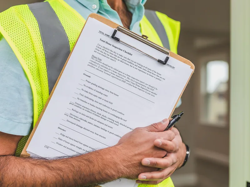 Inspection checklist clipped to a board beside a pen