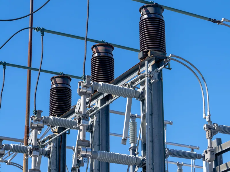 High-voltage electrical equipment and overhead conductors against a blue sky