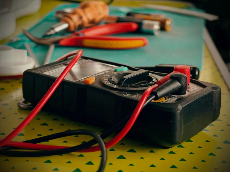 Digital multimeter with red and black probes on a workbench