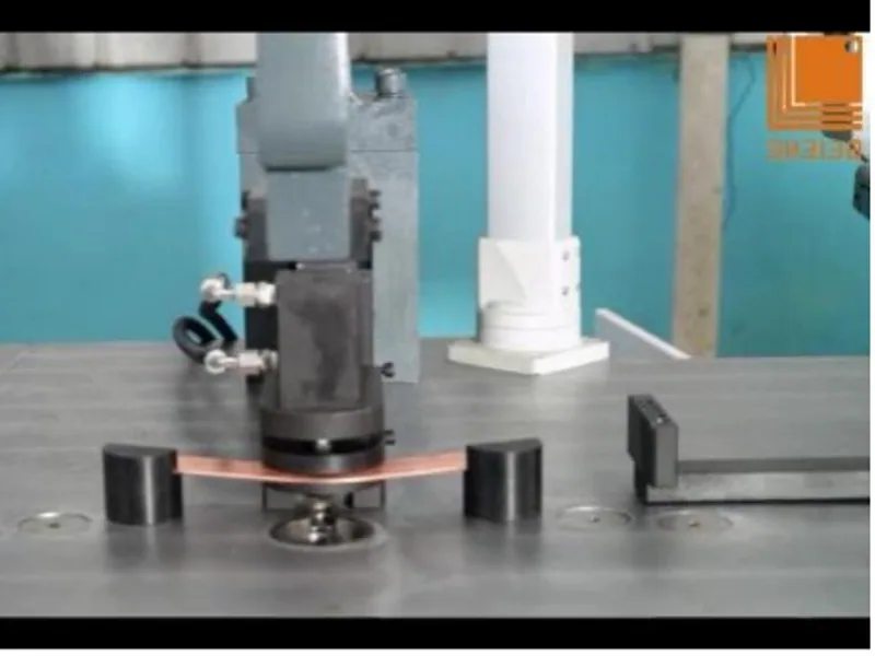 Formed copper busbar held in the tooling of a bending machine