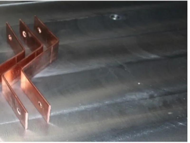 Formed copper parts resting on a clean metal workbench
