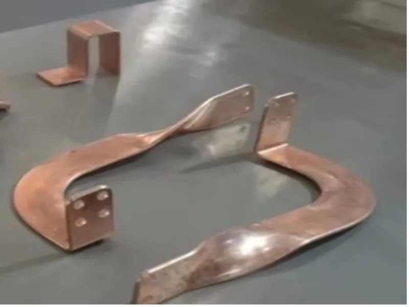 Finished copper bending samples arranged on a workbench