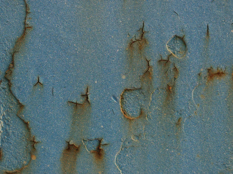 Cracks visible in the weathered coating of a metal surface