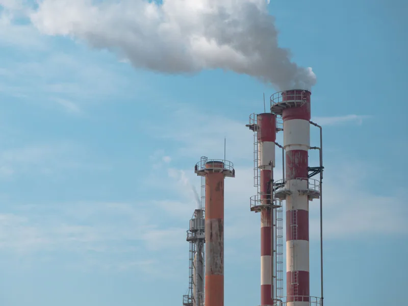 Industrial smokestacks releasing visible exhaust beneath a blue sky