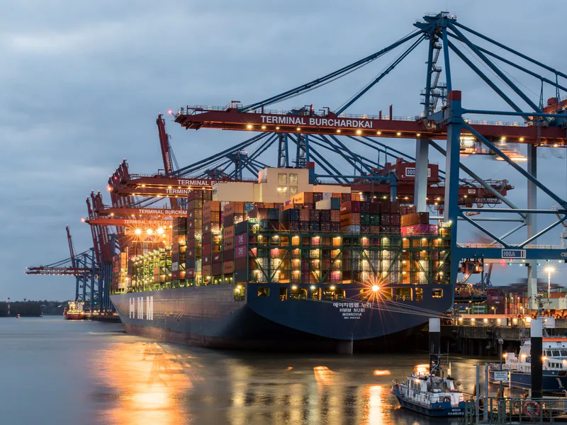 Container ship and port cranes representing international equipment freight