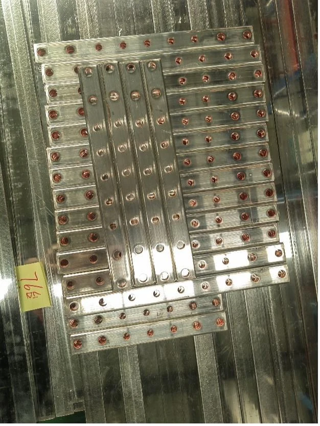 Straight copper busbar prototype samples with precision hole patterns on an inspection table